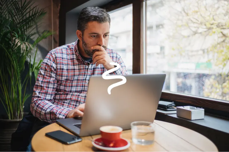 A small business owner concentrating on his laptop while working through his local SEO checklist, coffee on the table beside him