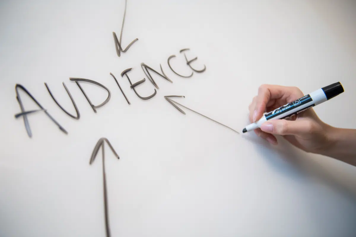 Hand writing the word "Audience" on a whiteboard with arrows pointing towards it