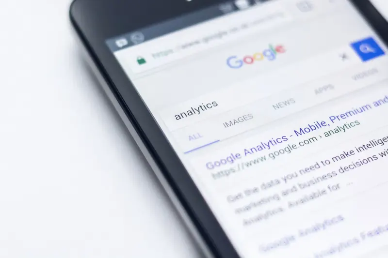 Close-up of a mobile phone showing Google search results for 'analytics'