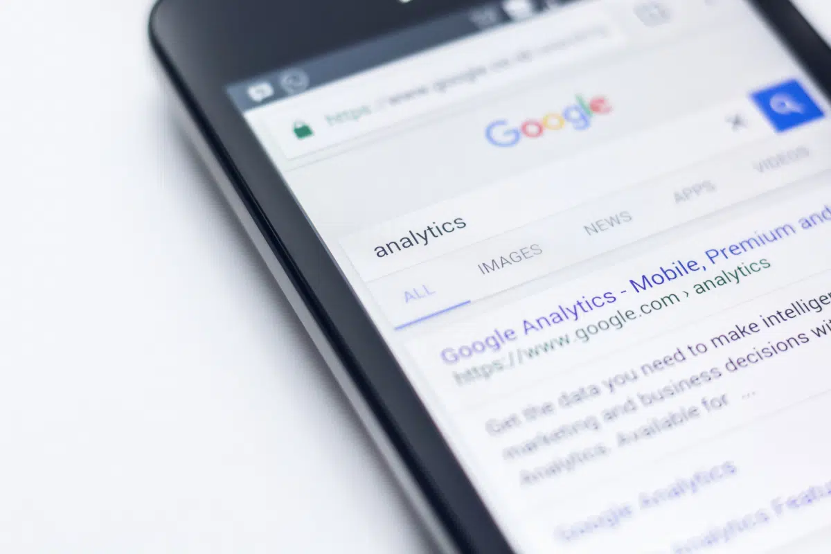 Close-up of a mobile phone showing Google search results for 'analytics'