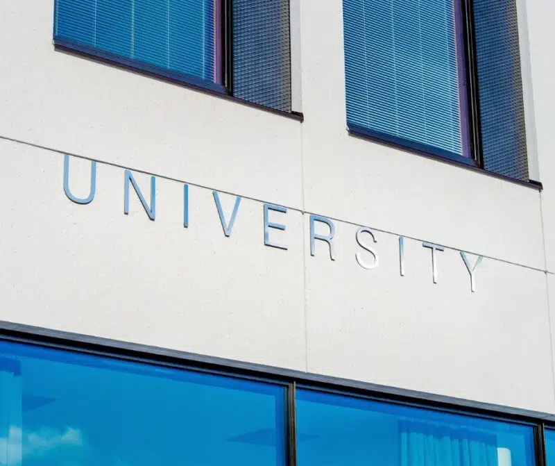 Close-up of a university building facade with the word 'University' in metal lettering