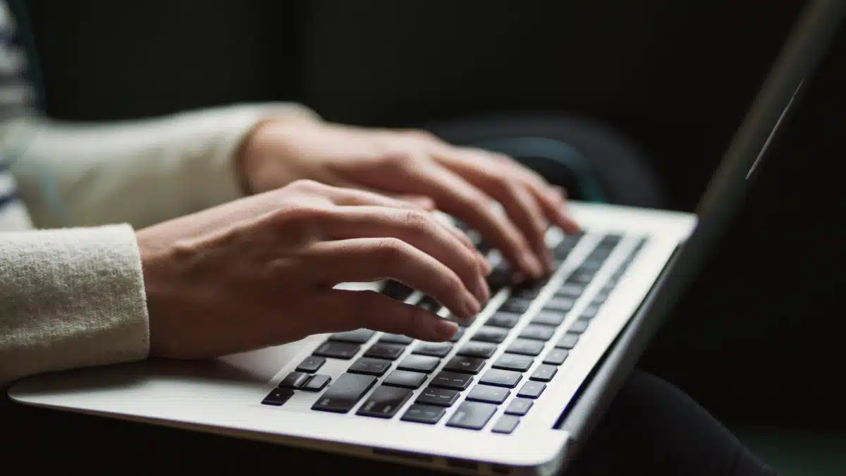 Close-up of hands typing on a laptop keyboard