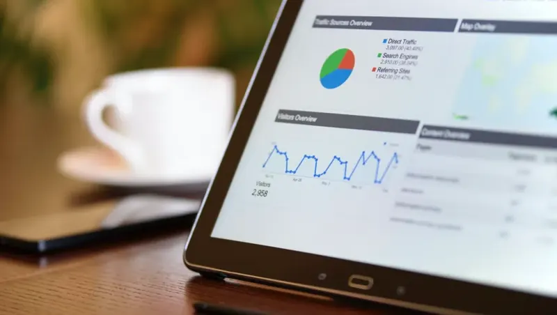 Tablet showing a Google Analytics dashboard with a traffic sources pie chart and visitors overview graph